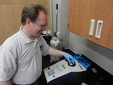 UCF Laboratory - Bob Macke, inserting 9.9 gram Sutter's Mill stone into pycnometer to measure bulk density. 